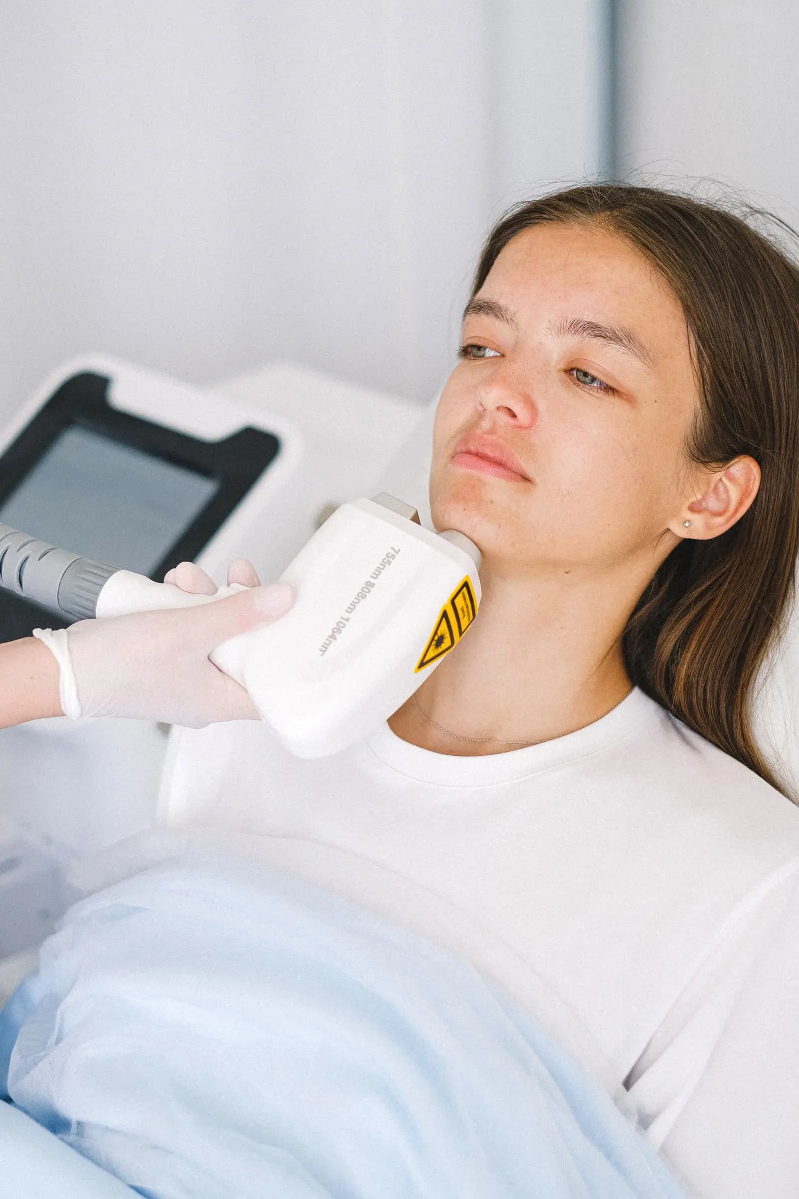 Laser handpiece held near the jaw during a laser facial